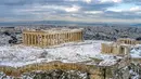 Bukit Acropolis kuno tertutup salju setelah hujan salju lebat di Athena, Yunani, Rabu (17/2/2021). Cuaca ekstrem nampaknya telah membuat suhu di Athena mencapai titik beku dan mengakibatkan salju turun di kota dengan penduduk lebih dari 3 juta jiwa ini. (Antonis Nikolopoulos/Eurokinissi via AP)