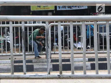 Seorang pria menerobos pagar pembatas jalan di kawasan Pasar Minggu, Jakarta, Kamis (5/4). Kondisi Jembatan Penyeberangan Orang (JPO) yang tak kunjung diperbaiki membuat warga nekat menyeberang lewat celah pagar pembatas. (Liputan6.com/Immanuel Antonius)