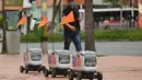 Robot pengiriman berjalan menyusuri jalan di Medellin, Kolombia, Selasa (21/4/2020). Robot yang bergerak dengan empat roda dengan bendera oranye di antena, membawa kiriman hingga berukuran 35 sentimeter persegi dan digunakan  mengantar pesanan restoran dengan pembayaran digital. (AP/Luis Benavides)