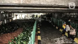 Warga berjalan melintasi taman yang sedang dibangun di kolong Jembatan Pegangsaan, Jakarta, Selasa (19/1/2021). Selain menjadi area interaksi warga sekitar, pembangunan taman di kolong jembatan tersebut untuk mempercantik kawasan bantaran kali. (merdeka.com/Iqbal S. Nugroho)