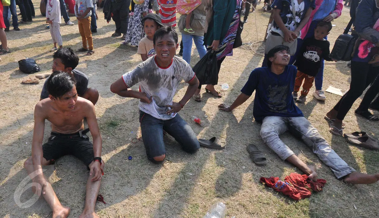 Sejumlah warga kelelahan usai mengikuti lomba Panjat Pinang Kolosal dalam rangka merayakan HUT RI ke-70 di Pantai Karnaval, Ancol, Jakarta, Senin (17/8). Sebanyak 124 batang pinang disediakan dengan berbagai ragam hadiah. (Liputan6.com/Herman Zakharia)