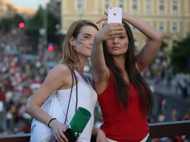Dua fans cantik asal Hungaria merayakan kemenangan timnya dengan berfoto selfie diatas gedung usai laga grup F Euro Cup 2016 antara Hungaria vs Portugal di Athletic Stadium, Margit Sziget, Budapest, (22/6/2016). (AFP/Ferenc Isza)
