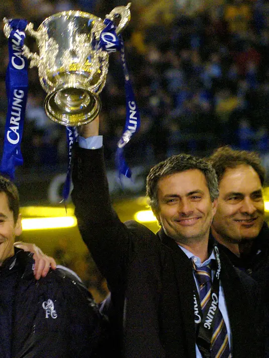 Pelatih Chelsea, Jose Mourinho tersenyum mengangkat trofi Piala Carling setelah mengalahkan Liverpool di final Piala Carling di Millennium Dome, Cardiff, Wales, 27 Februari 2005. Eks pelatih MU, Real Madrid dan Inter Milan itu dikontrak panjang hingga musim panas 2023. (AFP/Rebecca Naden)