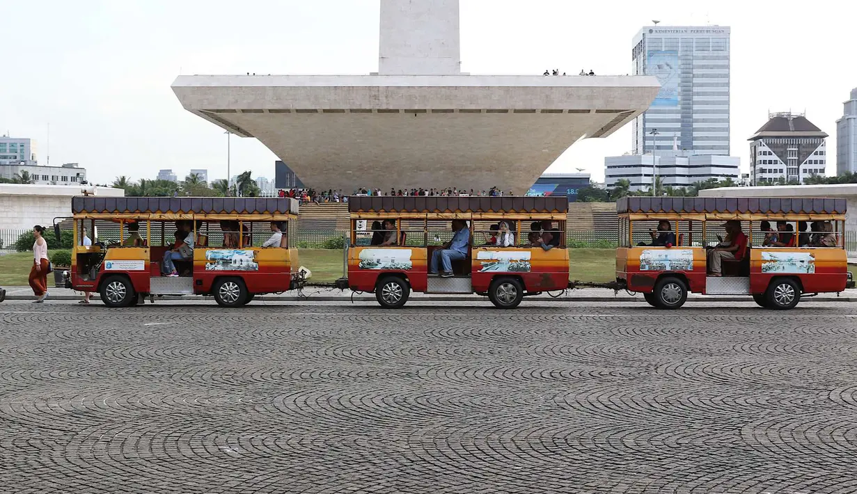 Wisatawan menaiki kereta wisata di kawasan Monumen Nasional (Monas), Jakarta, Sabtu (19/5). Kawasan wisata yang menjadi simbol ibukota tersebut menjadi salah satu lokasi warga untuk menunggu waktu berbuka puasa. (Liputan6.com/Immanuel Antonius)