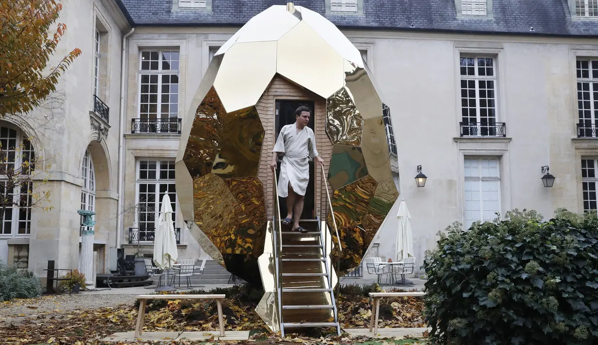 Seorang pria keluar dari Solar Egg, sebuah fasilitas sauna berbentuk telur raksasa, di Institut Swedia di Paris, Rabu (15/11). Untuk operasionalnya, Solar Egg menggunakan tenaga matahari, di mana panel surya pun terpasang di sana. (PATRICK KOVARIK / AFP)
