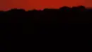 Seorang pria memotret matahari terbenam saat berperahu di Shawnee Mission Lake, Shawnee, Kansas, Amerika Serikat, Jumat (9/10/2020). Matahari terbenam terus lebih cerah dari biasanya karena asap dari kebakaran hutan barat terus melayang di seluruh negeri. (AP Photo/Charlie Riedel)