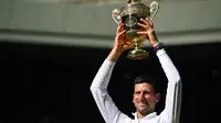 Petenis Serbia Novak Djokovic mengangkat trofi setelah mengalahkan Nick Kyrgios dari Australia dalam pertandingan final&nbsp;tenis Wimbledon 2022 di The All England Tennis Club, Wimbledon, London,&nbsp;Minggu, 10 Juli. (foto: SEBASTIEN BOZON / AFP)