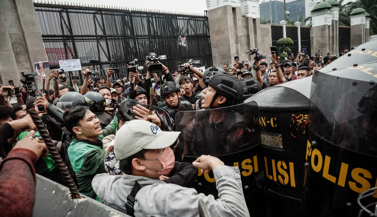 Pengunjuk rasa berusaha bertahan dan melawan dengan melempar botol air plastik. (YASUYOSHI CHIBA/AFP)