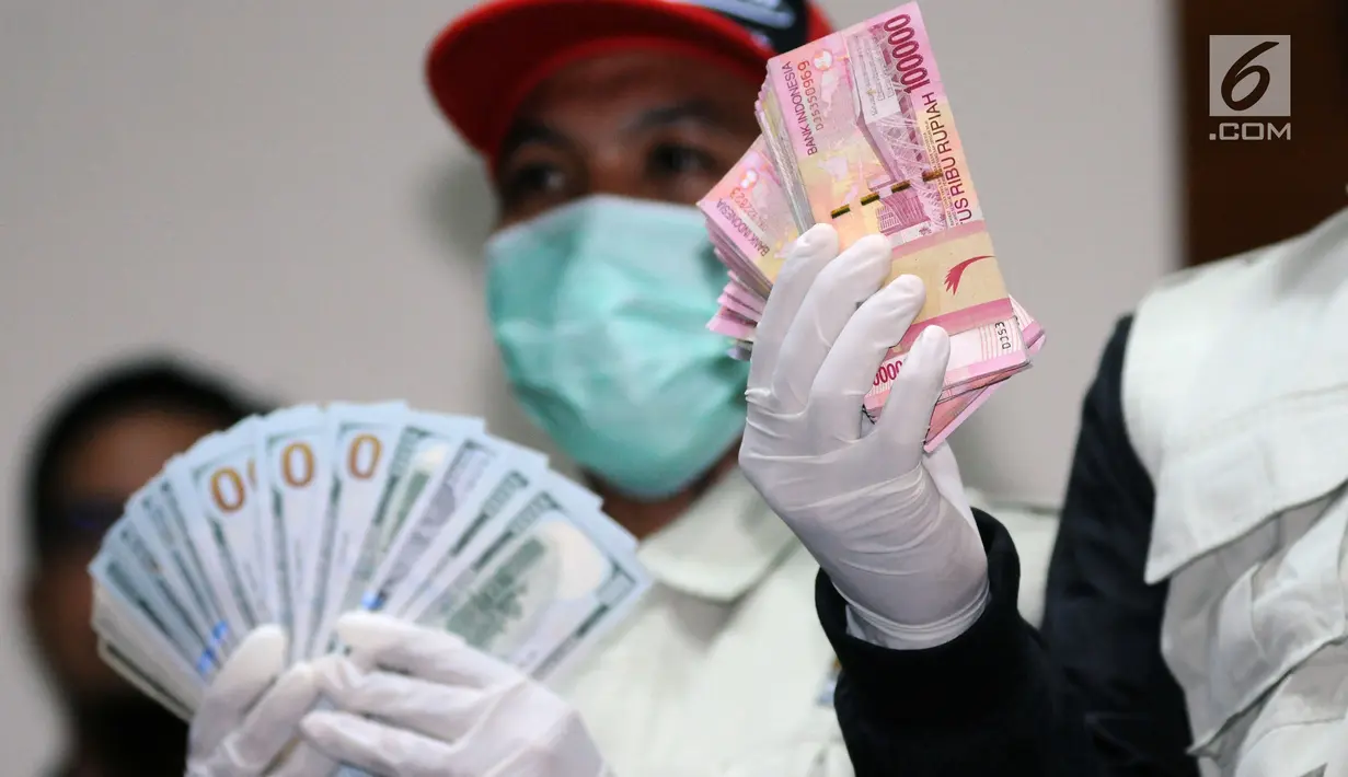Petugas KPK menunjukkan barang bukti uang pecahan rupiah dan dollar hasil operasi tangkap tangan Bupati Jombang, Nyono S Wihandoko di Gedung KPK, Jakarta, Minggu (4/2). KPK menyita uang Rp 25,5 Juta dan 9.500 US Dollar. (Liputan6.com/Helmi Fithriansyah)
