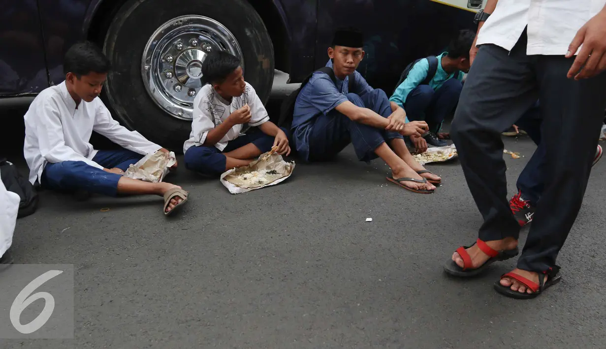 Sejumlah remaja makan siang di pinggir jalan sebelum memulai aksi di Medan Merdeka Timur, Jakarta, Jumat (4/11). Massa melakukan aksi di depan Istana Negara menuntut penegakan hukum kasus dugaan penistaan agama. (Liputan6.com/Faizal Fanani)