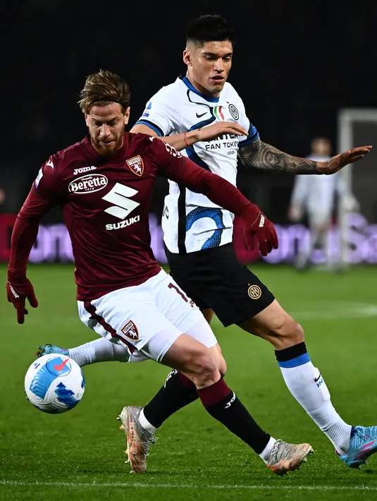 Bek Torino, Cristian Ansaldi (tengah)  berusaha mengontrol bola dari kawalan penyerang Inter Milan, Joaquin Correa selama pertandingan lanjutan Liga Serie A Italia di stadion Olimpiade di Turin, Senin (14/3/2022). Torino bermain imbang atas Inter Milan 1-1. (AFP/Marco Bertorello)
