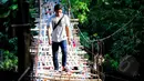 Seorang lelaki berjalan di atas jembatan bambu yang menghubungkan Kampung Bambon, Jakarta Selatan dan Kelapa Dua Depok, Depok, Jumat (13/3/2015). (Liputan6.com/Yoppy Renato)