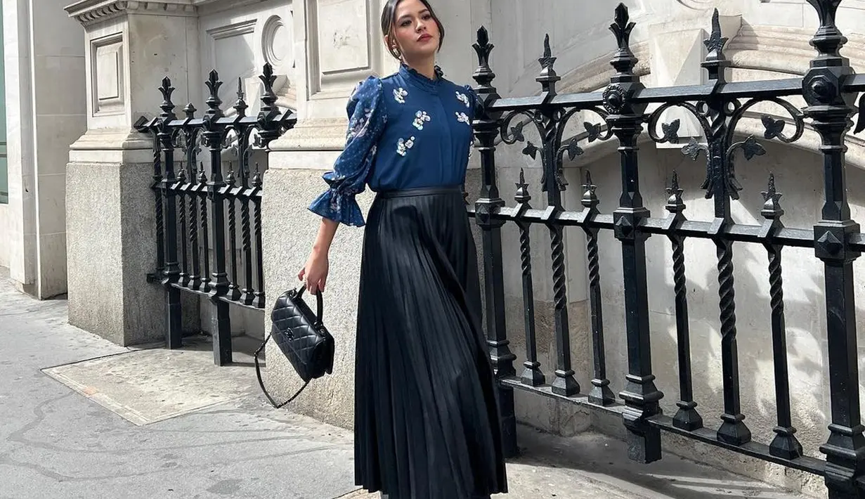 Raisa tampil chic di sudut jalan di London. Ia tampak berpose mengenakan long sleeve blouse berwarna biru dengan detail embroidery berbentuk bunga-bunga putih, ia padukan dengan pleats skirt hitam yang panjang, heels boots, dan hand bag yang sama-sama berwarna hitam. Foto: Instagram.