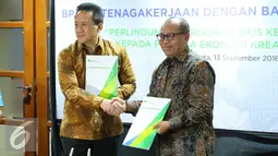 Dirut BPJS Ketenagakerjaan Agus Susanto (kanan) berjabat tangan dengan Kepala Badan Ekonomi Kreatif Triawan Munaf usai menandatangani nota kesepahaman di Jakarta, Rabu (13/9). (Liputan6.com/Angga Yuniar)