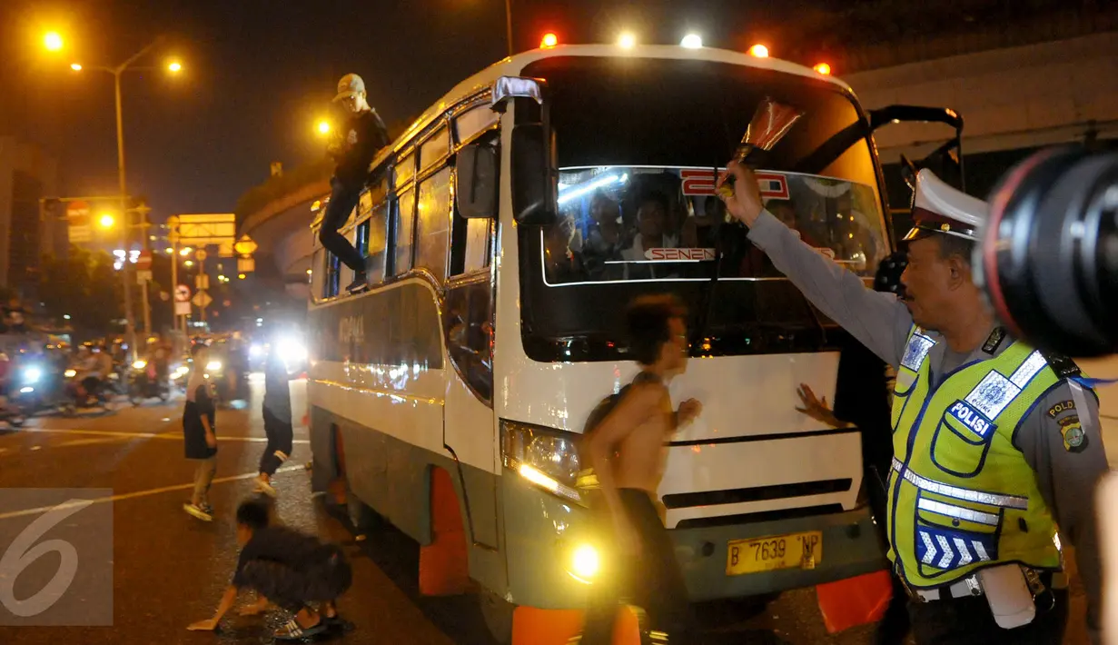 Petugas memberhentikan bus kota karena menaikan penumpang diatap bus saat malam takbiran di kawasan Matraman, Jakarta Timur, Jum’at (17/7/2015) malam. Tindakan tersebut dapat membahayakan keselamatan penumpang dan orang lain.(Liputan6.com/Faisal R Syam)