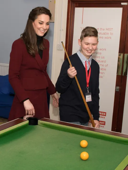 Kate Middleton bermain biliar bersama seorang anak, Craig Davis saat kunjungannya ke MIST, sebuah tempat kesehatan mental bagi anak di Pontypool, Wales, Inggris (22/2). Kate terlihat menikmati permainan biliar tersebut. (AFP Photo / Pool / Paul Edwards)