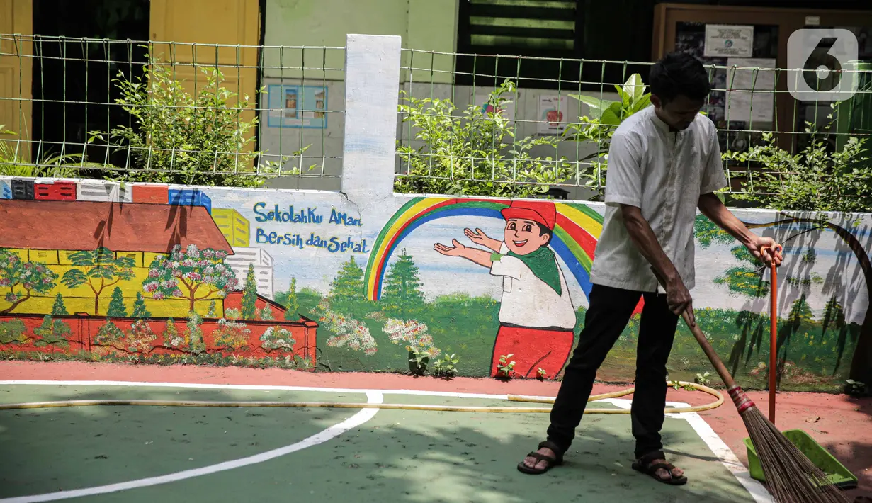 Petugas menyapu lapangan di sekolah di SD Negeri Kota Bambu 03/04, Jakarta, Sabtu (21/11/2020). Pemerintah pusat memberikan kewenangan pemerintah daerah membuka sekolah dan melakukan pembelajaran tatap muka pada semester genap tahun ajaran 2020/2021. (Liputan6.com/Faizal Fanani)