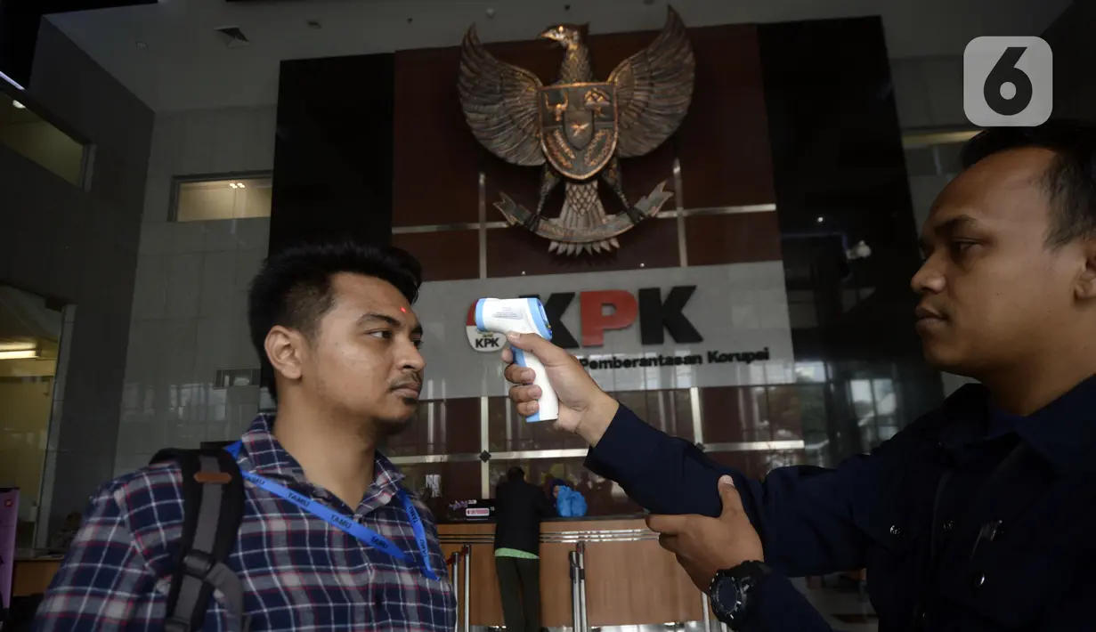Petugas mengecek suhu tamu dan pegawai yang akan masuk ke Loby di Gedung KPK, Jakarta, Kamis, (12/3/2020). KPK menerapkan pengecekan suhu tubuh tersebut untuk mengantisipasi penyebaran virus corona atau covid-19. (merdeka.com/Dwi Narwoko)