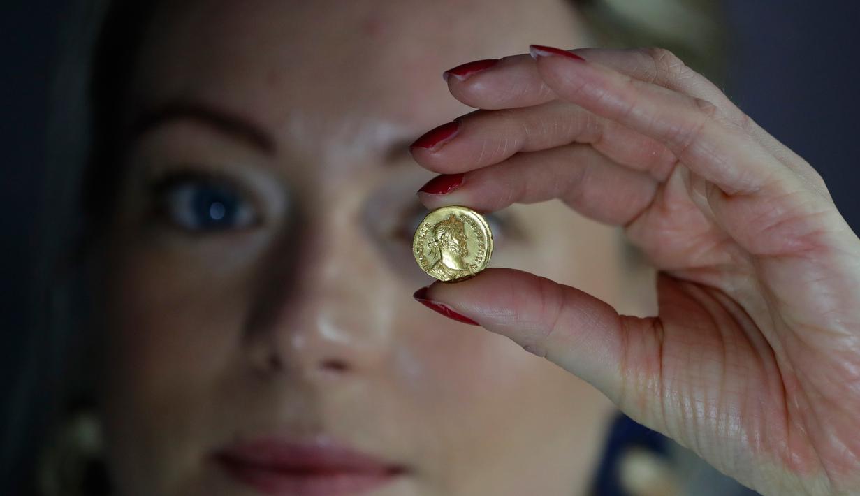 Seorang karyawan Dix Noonan Webb menunjukkan koin Romawi kuno di London, Inggris (28/5/2019). Koin emas ini diperkirakan akan mendapatkan jumlah enam angka ketika itu ditawarkan oleh Dix Noonan Webb dalam lelang dua hari mereka pada bulan Juni. (AP Photo/Kirsty Wigglesworth)