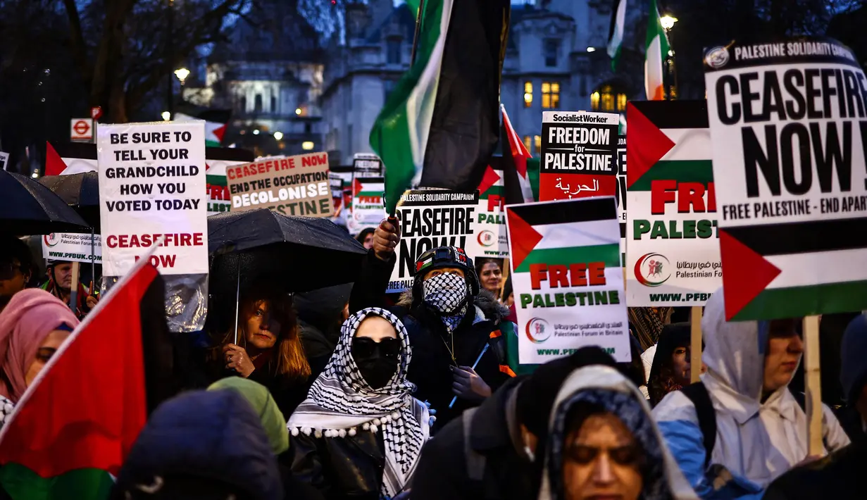 Para demonstran pro-Palestina melambaikan bendera Palestina dan memegang plakat saat berunjuk rasa di Parliament Square, London pada 21 Februari 2024. (HENRY NICHOLLS/AFP)