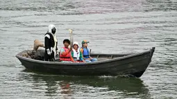 Sejumlah pemegang obor Olimpiade menaiki perahu saat upacara pembukaan Olimpiade Paris 2024, Prancis, 26 Juli 2024. (AFP/Miguel Medina)