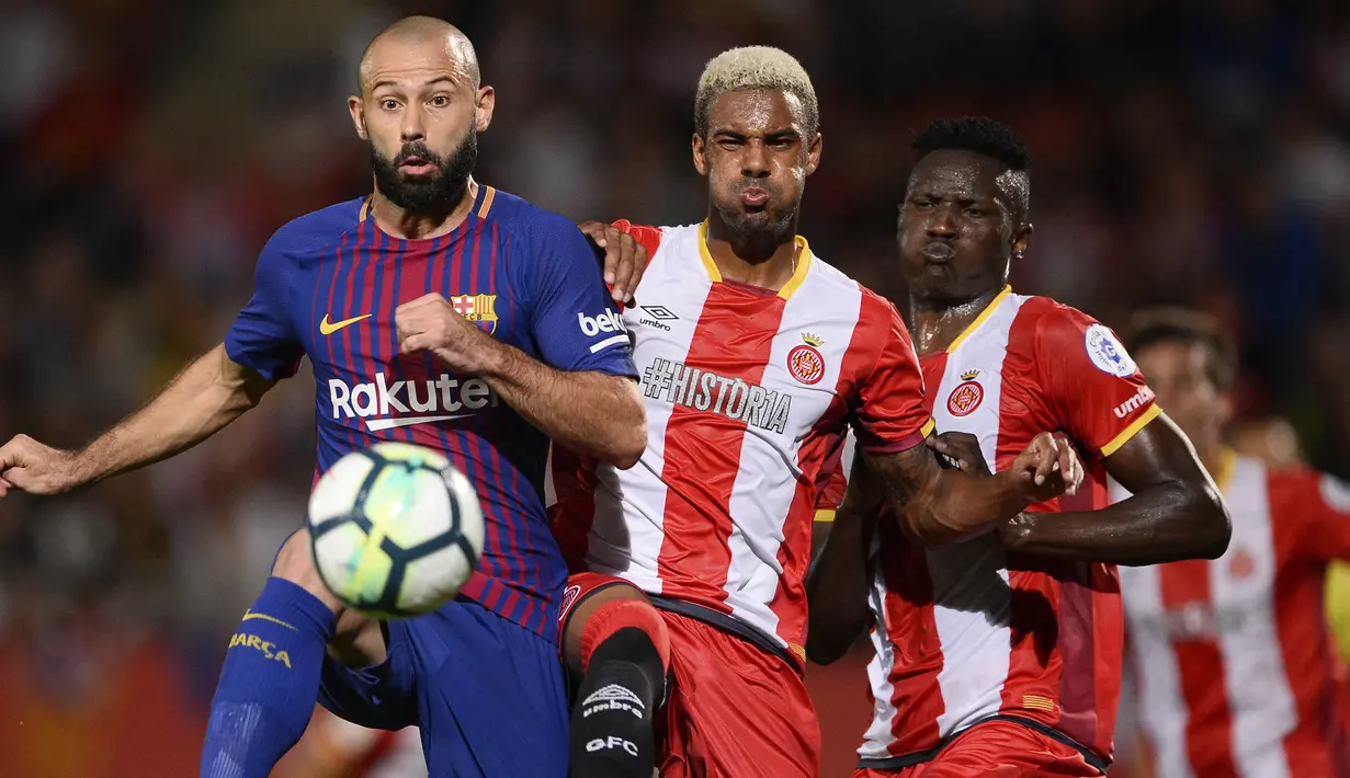 Bek Barcelona, Javier Mascherano, mengamankan bola dari bek Girona, Jonas Ramalho, pada laga La Liga Spanyol di Stadion Montilivi, Girona, Sabtu (23/9/2017). Girona kalah 0-3 dari Barcelona. (AFP/Josep Lago)