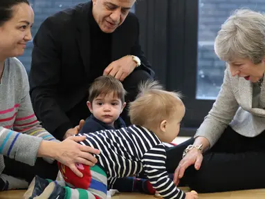 Perdana Menteri Inggris Theresa May bermain dengan bayi saat berkunjung ke pusat kesehatan di London, Inggris, Kamis (22/11). Theresa menjabat sebagai Perdana Menteri Inggris sejak 2016. (Andrew Matthews/Pool via AP)