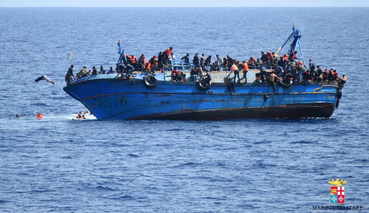 Sebuah perahu yang menampung 500 lebih imigran asal Timur Tengah tersebut tampak miring sebelum akhirnya terbalik dan tenggelam di lepas pantai Libya, Rabu (25/5). Kandasnya perahu diduga akibat kelebihan muatan. (STR/AFP MARINA MILITARE/AFP)