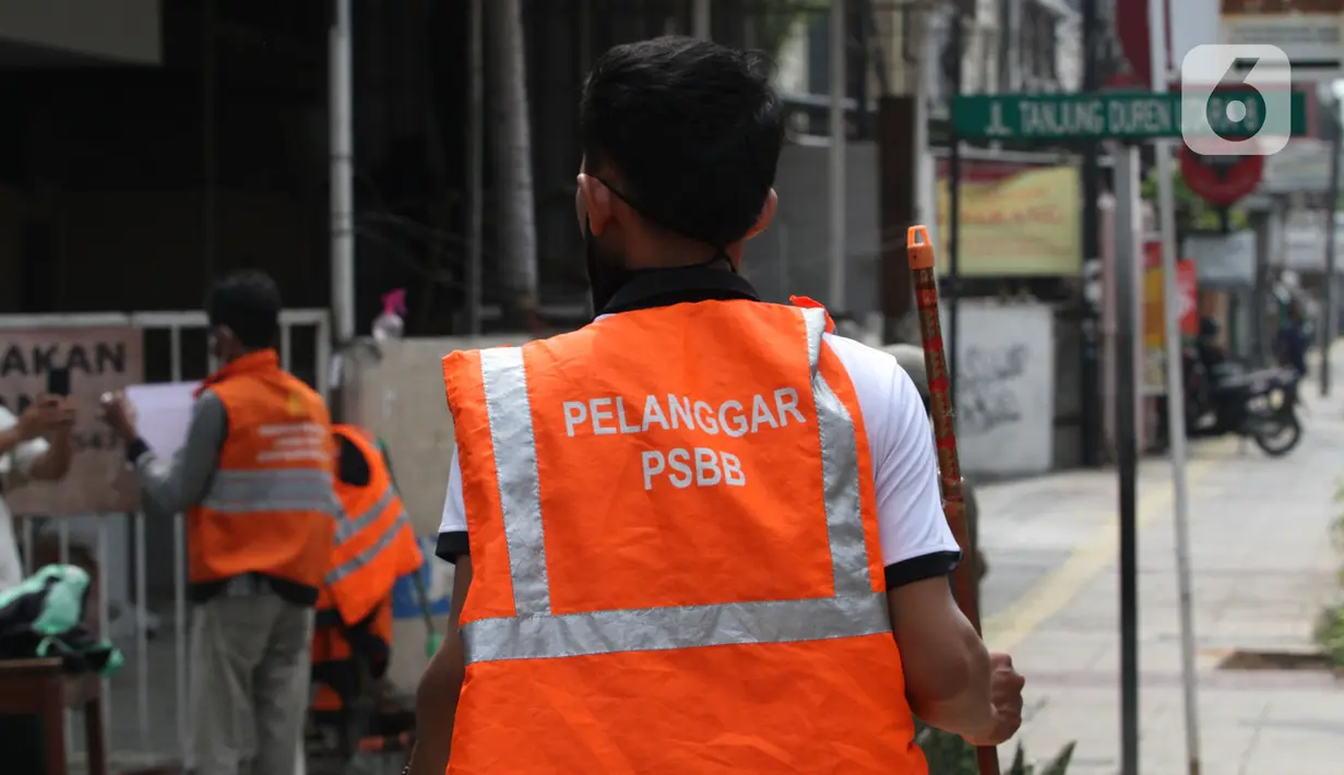 Warga pelanggar PSBB dihukum menyapu saat terjaring razia masker di Jalan Tanjung Duren Raya, Jakarta, Jumat (11/9/2020). Petugas Satpol PP gencar melakukan razia masker menyusul kasus COVID-19 di DKI Jakarta yang terus meningkat. (merdeka.com/Imam Buhori)