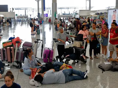 Calon penumpang menunggu jadwal keberangkatan pesawat di bandara Hong Kong, Rabu (14/8/2019). Bandara Hong Kong kembali membuka penerbangan keberangkatan pada Rabu pagi setelah sempat lumpuh selama dua hari akibat demonstran menduduki salah satu bandara tersibuk di dunia tersebut. (AP/Vincent Thian)