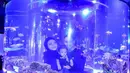 Dalam foto ini, Nathalie Holscher dan Fariz Utama memanfaatkan aquarium berbentuk tabung raksasa transparan yang merefleksikan keduanya bersama baby Adzam. Membiaskan cahaya ungu kebiruan, ketiganya asyik menikmati sejumlah ikan yang berenang di dalam tabung kaca. Hubungan baby Adzam dan Fariz Utama tampak hangat sekaligus dekat. (Foto: Dok. Instagram @farizutama30)
