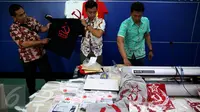 Petugas menunjukkan barang bukti saat rilis penangkapan tersangka penjual kaus berlogo palu arit secara online di Bareskrim Polri, Jakarta, Jumat (30/12). HS ditangkap karena dianggap menyebarkan paham komunisme dan marxisme (Liputan6.com/Johan Tallo)