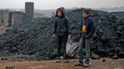 Dua anak Suriah mengangkut batu bara saat mereka bekerja di kilang minyak darurat dekat Kota al-Bab yang dikuasai Turki, Suriah, 20 November 2021. Sebanyak 1,6 juta anak Suriah juga berisiko putus sekolah. (Bakr ALKASEM/AFP)