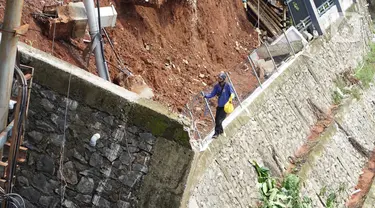 Petugas melintas di dekat turap yang hancur di Jalan Damai, Ciganjur, Jakarta Selatan, Minggu (11/10/2020). Hujan yang deras sejak Sabtu (10/10/2020) sore mengakibatkan kawasan tersebut mengalami banjir sekaligus longsor. (Liputan6.com/Immanuel Antonius)