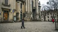 Seorang wanita berjalan melewati Museum Sejarah Agama di Lviv, Ukraina, 4 Maret 2022. Pekerja merakit wadah logam di teras museum untuk menyimpan barang-barang dengan aman sebelum menempatkannya pada ruang bawah tanah untuk berjaga-jaga jika invasi Rusia maju ke barat. (AP Photo/Bernat Armangue)