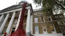 Anna Wigley mendongak ke arah karya seni bunga poppy bertajuk 'Weeping Window' di The Imperial War Museum, London, Kamis (4/10). Musuem tersebut tampak seperti berdarah dengan pajangan karya seni bunga poppy. (AP Photo/Kirsty Wigglesworth)