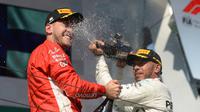 Pembalap Mercedes, Lewis Hamilton, menyemprotkan sampanye kearah pembalap Ferrari, Sebastian Vettel saat berselebrasi mejuarai GP Hungaria di Sirkuit Hungaroring, Mogyorod, (29/7). (Zoltan Balogh/MTI via AP)