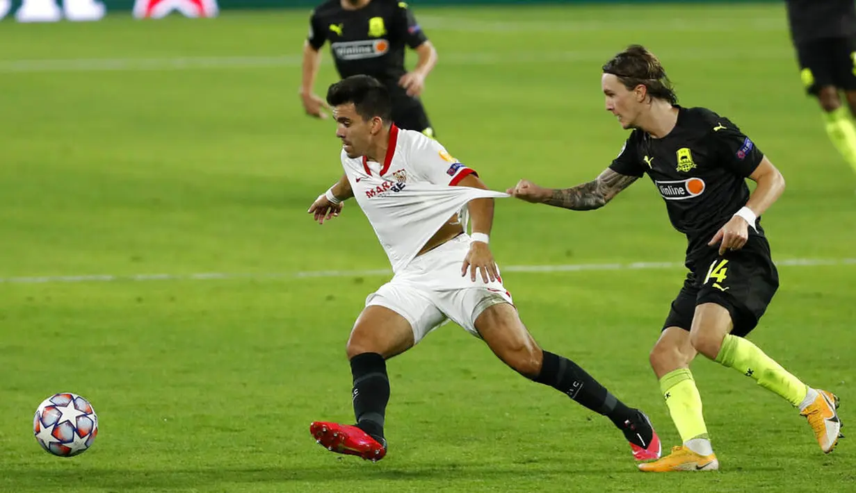 Kiper Krasnodar, Kristoffer Olsson, berebut bola dengan pemain Sevilla, Marcos Acuna, pada laga Liga Champions di Stadion Ramon Sanchez Pijuan, Kamis (5/11/2020). Sevilla menang dengan skor 3-2. (AP Photo/Miguel Morenatti)