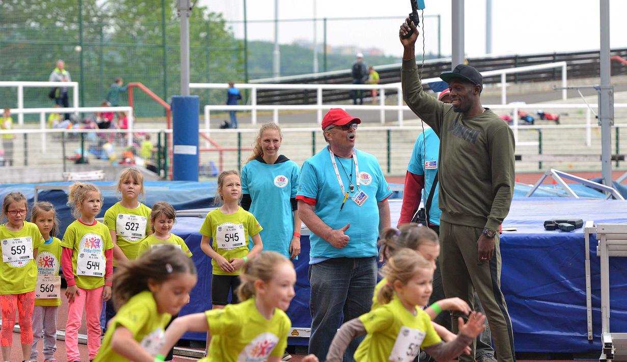 Usain Bolt membuka menembakan pistol tanda start pada lomba lari untuk anak-anak di Prague. Bolt datang ke Republik Ceska guna mengikuti pertemuan Golden Spike di Ostrava pada Jumat 20 mei 2016, (18/5/2016). (AFP/Michal Cizek)