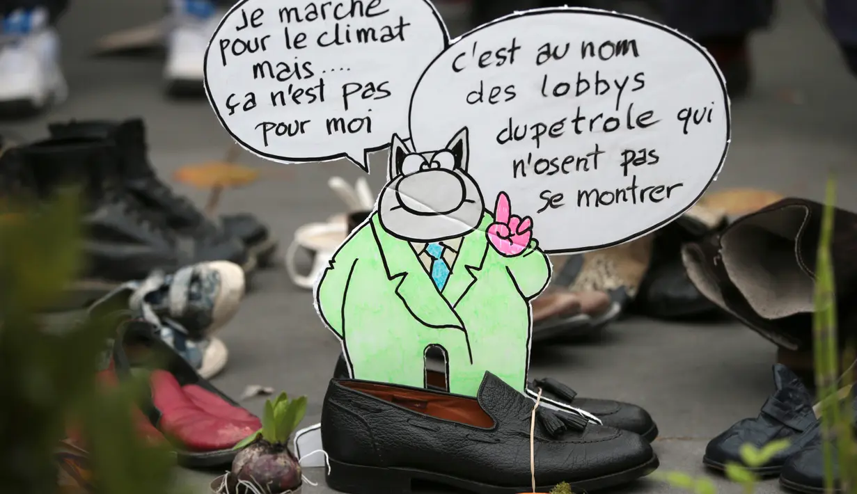 Sebuah pesan diletakkan diantara sepatu yang dipajang di place de la Republique, Prancis, sebagai tanda solidaritas karena pawai lingkungan di Paris dibatalkan jelang KTT Perubahan Iklim, Minggu (29/11).(AFP PHOTO/Joel SAGET)