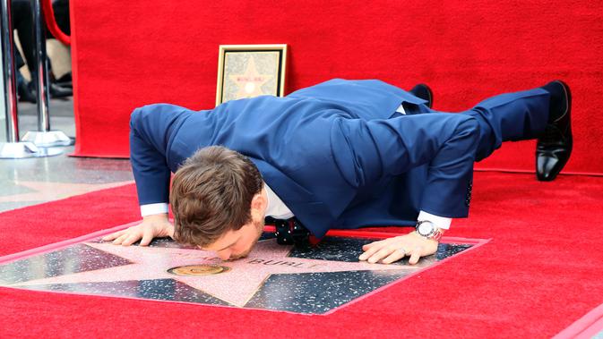 Michael Buble mencium bintang Hollywood Walk Of Fame miliknya saat acara penghargaan di Hollywood, California (16/11). Penyanyi Jazz asal Kanada ini merupakan penerima bintang ke 2,650 di Hollywood Walk Of Fame. (AFP Photo/David Livingston)