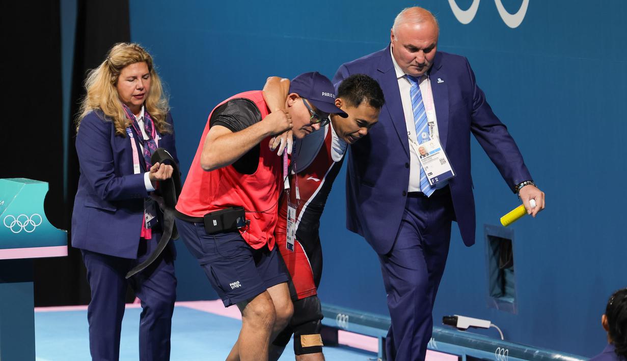 Lifter Indonesia, Eko Yuli Irawan dipapah keluar arena oleh ofisial setelah gagal melakukan angkatan clean and jerk pada cabang olahraga angkat besi 61 kg putra Olimpiade 2024 di South Paris Arena, Paris, Prancis, Rabu (07/08/2024). (Dok. NOC Indonesia/Naif Muhammad Al'as)