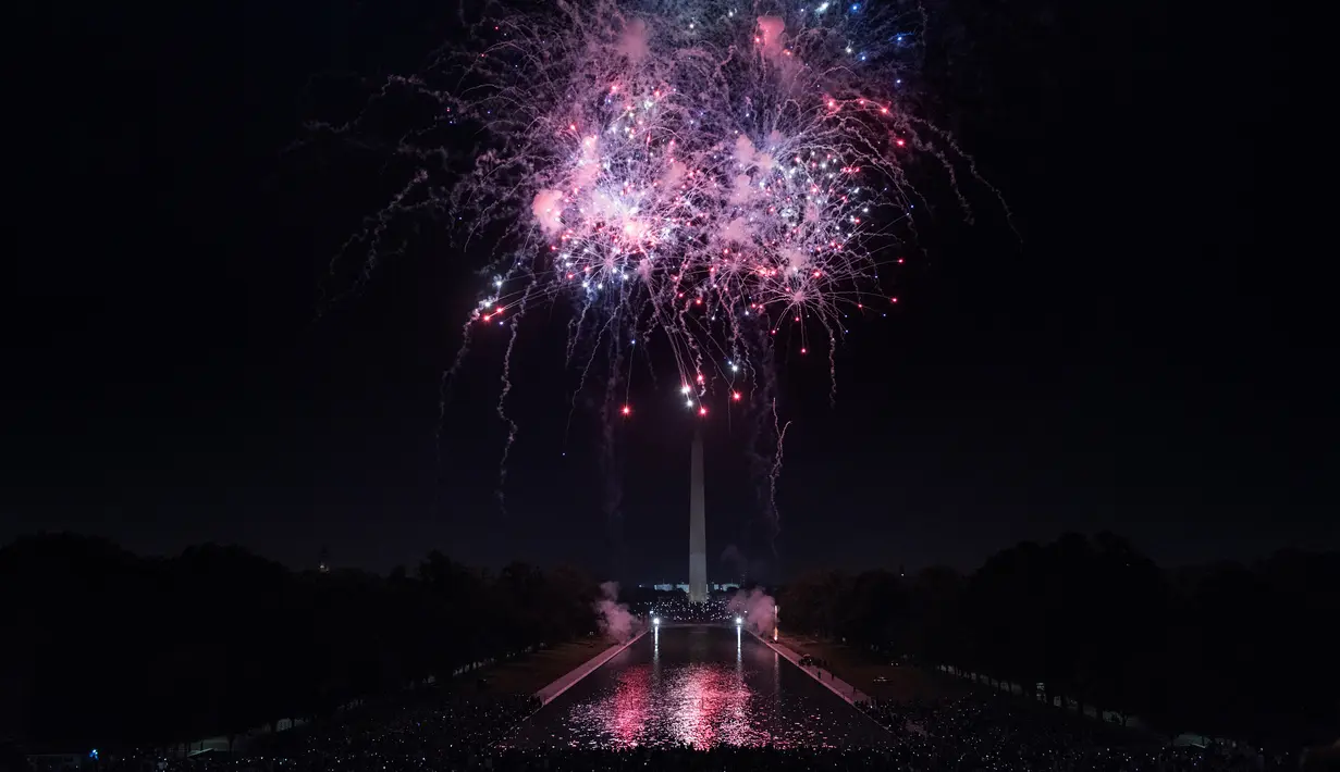 Sejumlah orang menonton kembang api saat perayaan hari kemerdekaan AS di Washington DC (4/7). Hari tersebut memperingati disahkannya Deklarasi Kemerdekaan oleh Kongres Kontinental Kedua pada 4 Juli 1776. (AFP Photo/Brendan Smialowski)