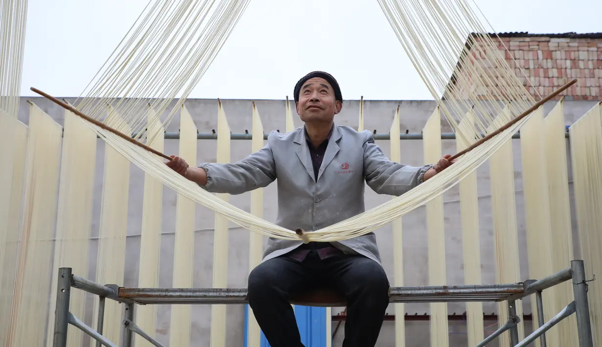 Seorang penduduk desa membentangkan mi di Desa Huangjiazhuang di Distrik Maiji, Kota Tianshui, Provinsi Gansu, China barat laut, pada 30 November 2020. Proses pembuatan mi di desa tersebut memiliki sejarah lebih dari 200 tahun. (Xinhua/Ma Xiping)
