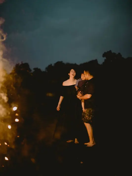 Perayaan Tahun Baru Laura Basuki bersama keluarga kecilnya. Laura Basuki tampil elegan dengan off-the-shoulder dress berwarna hitam, sedangkan sang suami yang menggendong buah hati mereka tampil kasual dengan kaus dan celana pendek. [Foto: Instagram/laurabas]