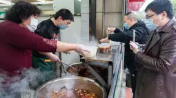Para pelanggan membeli mi sapi di sebuah restoran di Xiangyang, Provinsi Hubei, China tengah, pada 16 Maret 2020. Beberapa restoran mi sapi di Xiangyang kembali melanjutkan bisnis dengan layanan take away pada Senin (16/3). (Xinhua/Xie Jianfei)