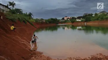 Anak-anak memancing pada bagian proyek pembangunan tol Cinere-Serpong yang berubah menjadi danau sedalam 4 meter di kawasan Cipayung, Tangsel, Banten (17/1). Pembangunan jalan Tol ini sepanjang 10,14 kilometer. (Merdeka.com/Arie Basuki)
