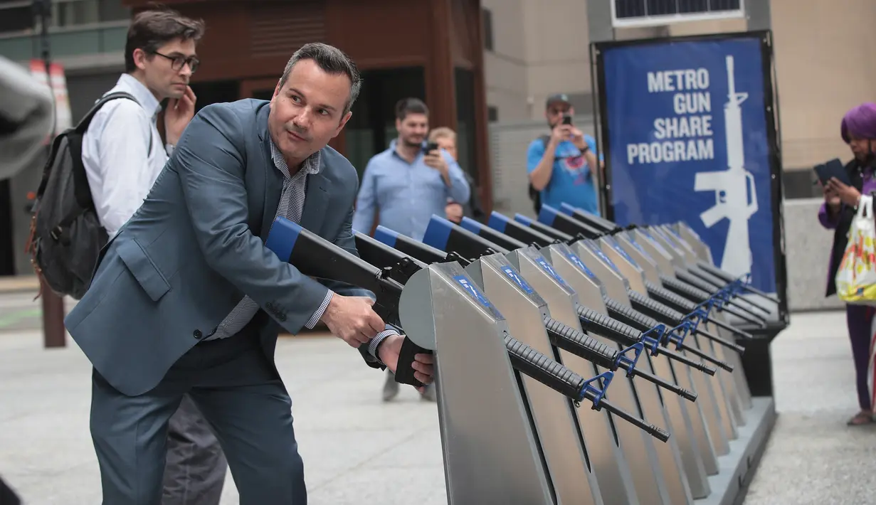 Seorang pria memegang senjata api yang merupakan instalasi seni dari Program Chicago Gun Share di Daley Center Plaza, Chicago, Illinois (14/5). (Scott Olson / Getty Images / AFP)