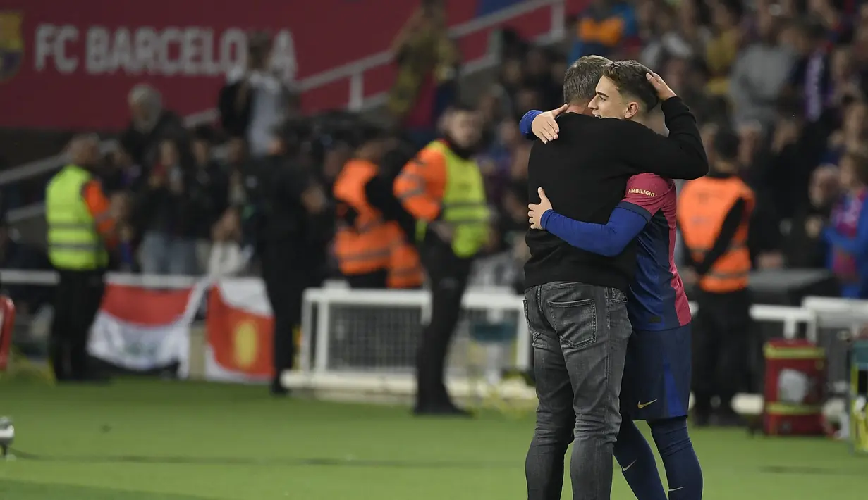 Pemain Barcelona, Gavi (kanan) memeluk pelatih Hansi Flick sebelum masuk menggantikan Pedri pada laga lanjutan Liga Spanyol 2024/2025 yang berlangsung di Estadi Olimpic Lluis Companys, Barcelona, Spanyol, Senin (21/10/2024) dini hari WIB. (AFP/Josep Lago)