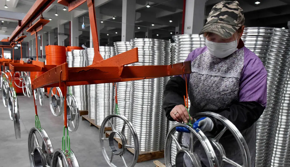 Seorang pekerja wanita mengecek kondisi pelek di pabrik pembuatan pelek sepeda motor di Jinhua, Provinsi Zhejiang, China (14/1). (AFP Photo/China Out)